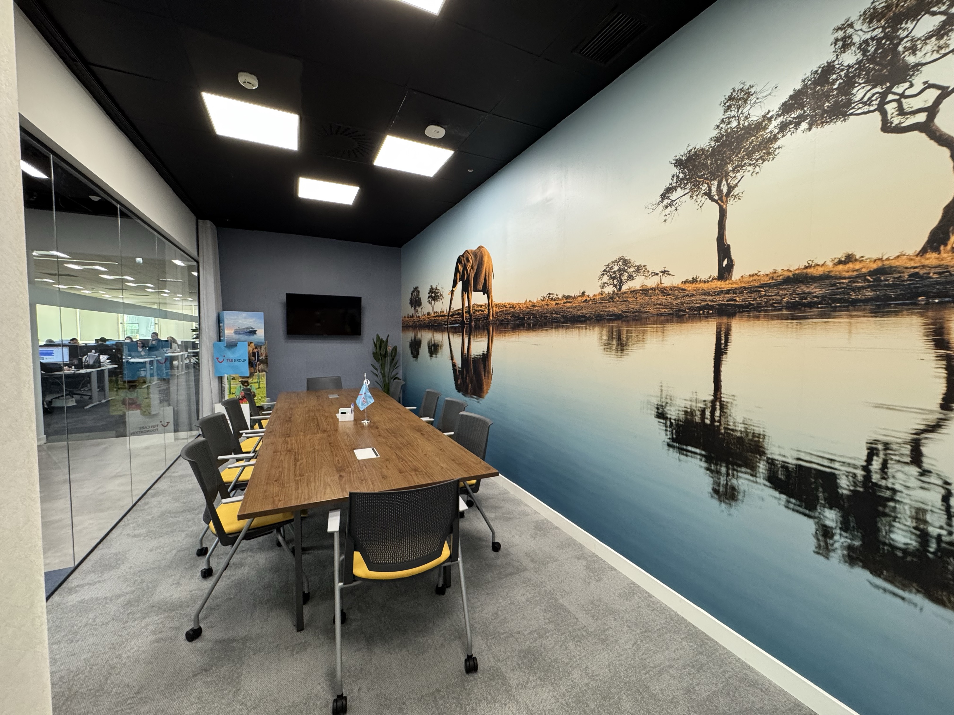 a meetign room with safari wallpaper in the background is a open work space with people working