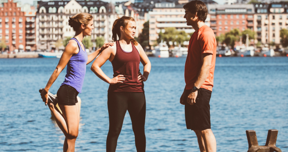 Three TUI colleagues in running clothes stand next to a lake in Sweden following a run.