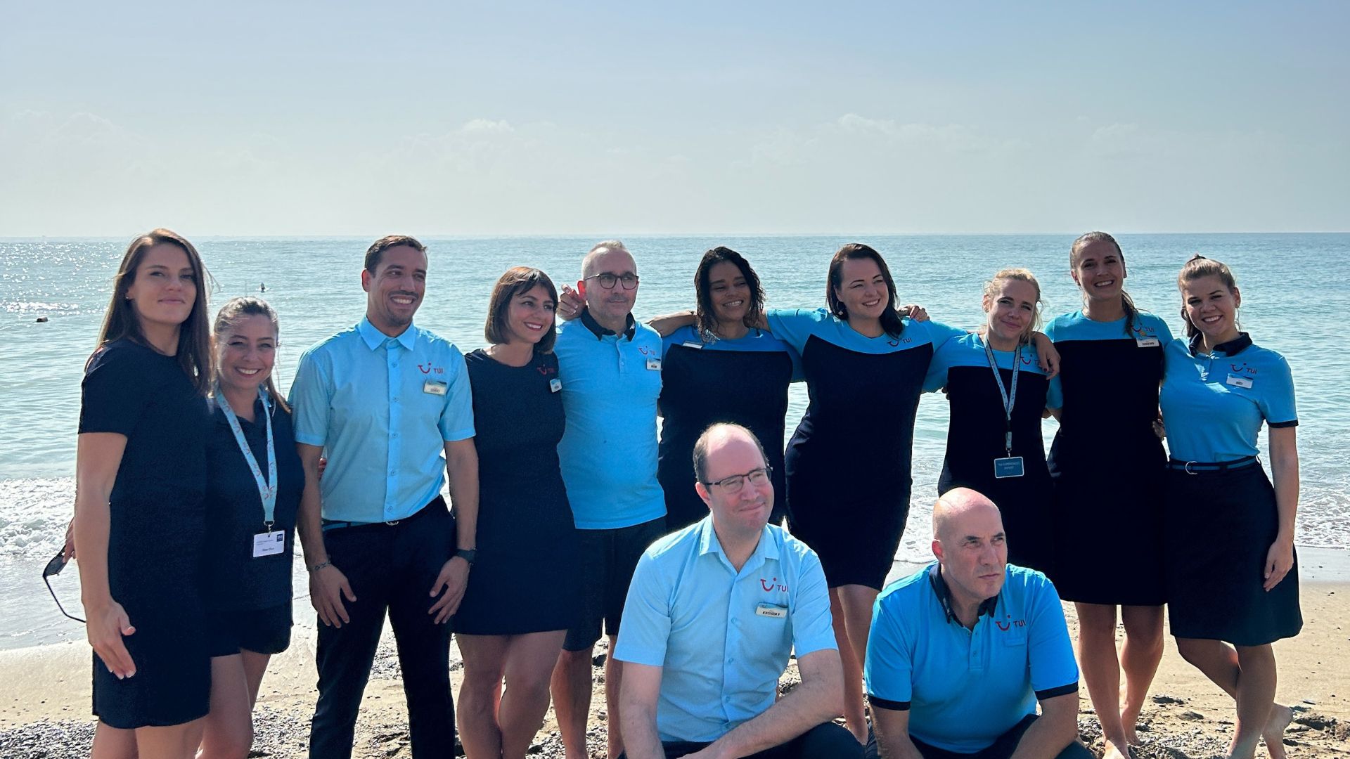 A group of TUI colleagues standing in front of the beach