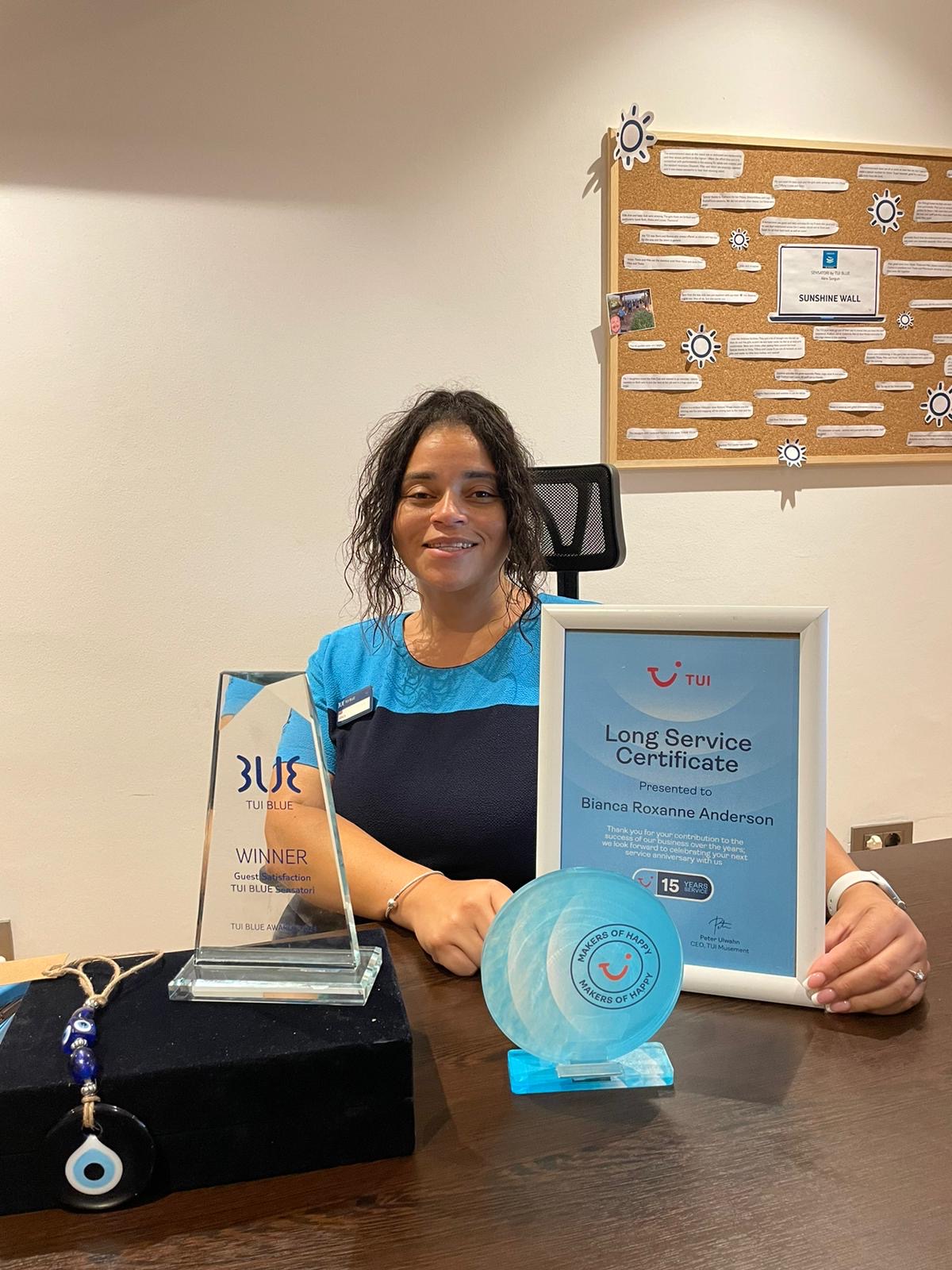 A woman in her TUI uniform showing her award