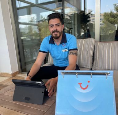 A TUI Hotel Rep smiles next to his iPad in a TUI hotel