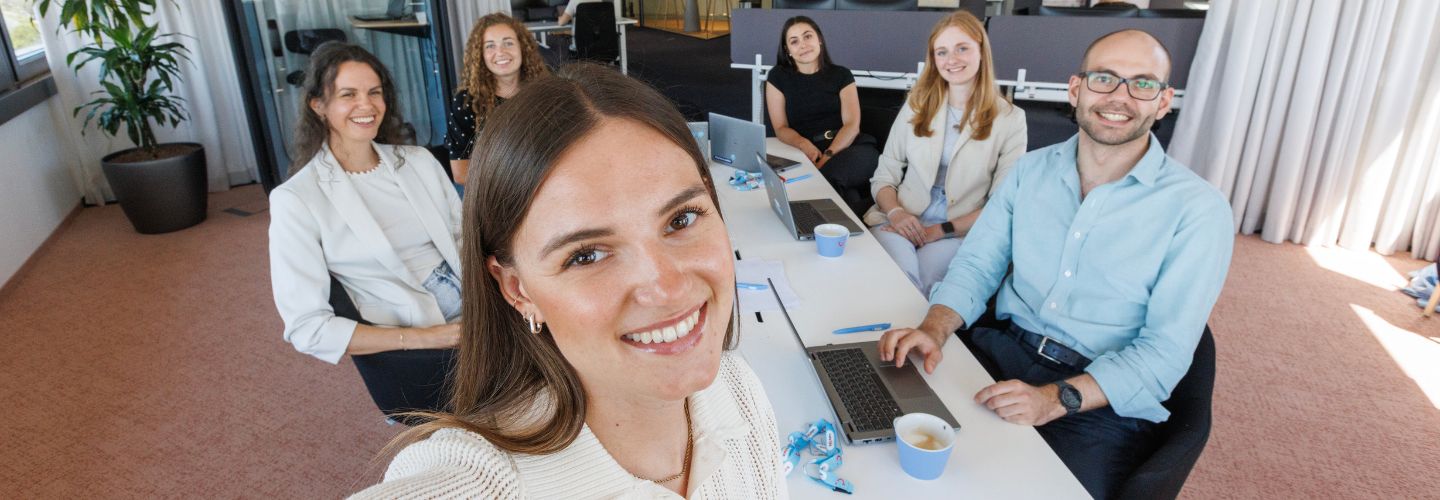 A group of TUI colleagues take a selfie whilst sat at a conference desk in a TUI office