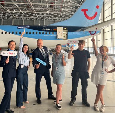 A group of TUI Airline colleagues pose together next to a TUI aircraft in the Belgium hangar