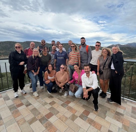 A large group of TUI Talent Acquisition colleagues stand together in an outdoor setting