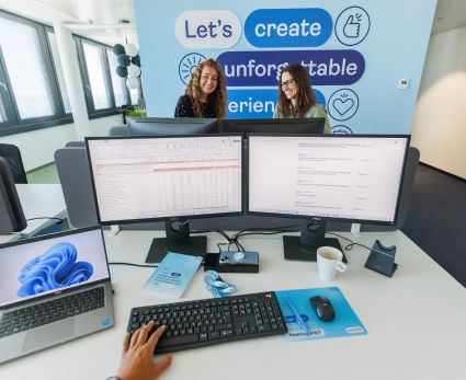 An eagle eye image of a TUI colleague sat at their desk with two colleagues sat in front with TUI branding