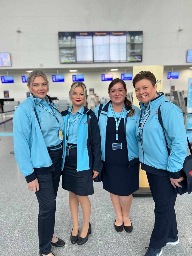 A group of female airport reps in uniform standing inside the airport