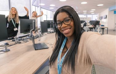 A TUI colleague with a headset on takes a selfie smiling at her desk