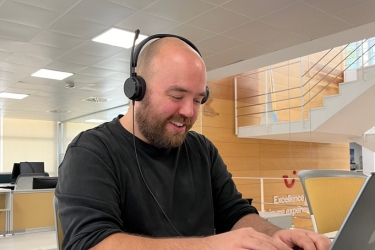A male colleague working behind his laptop with his headset op