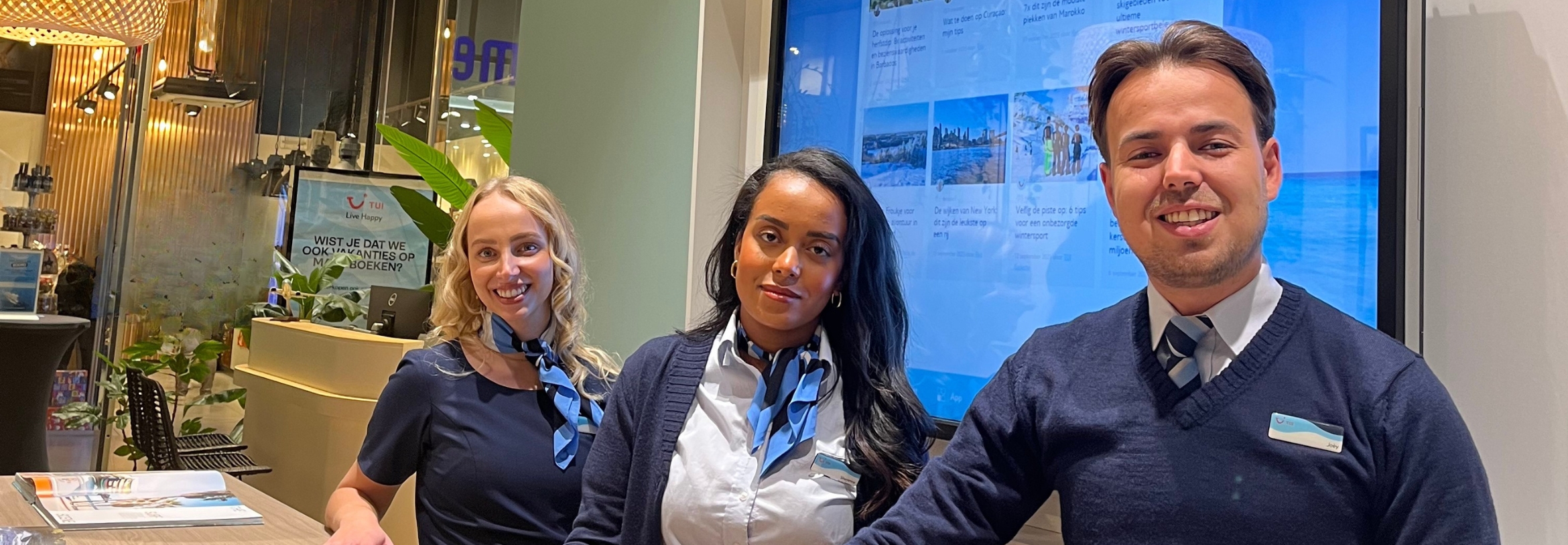 drie TUI medewerkers in de shop die lachen naar de camera