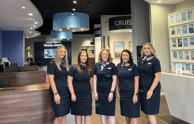 Een groep van vijf retailmedewerkers die naar de camera glimlachen