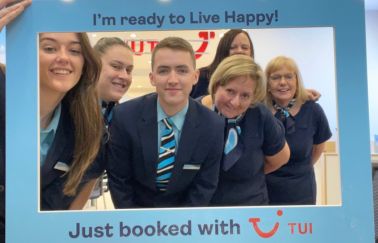 A group of six TUI Retail employees posing with a board that says I just booked with TUI