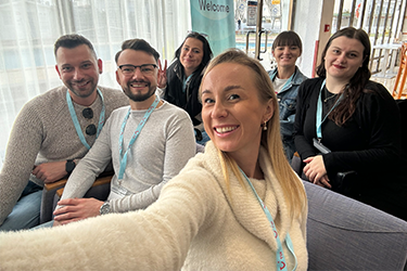 Six TUI colleagues sat down smiling at the camera with a netted window in the background. They are all wearing TUI lanyards.