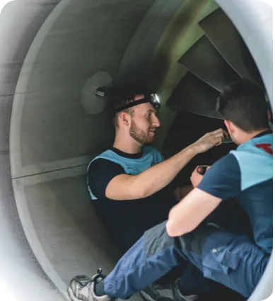 Aircraft engineer in TUI uniform performing maintenance on an aircraft inside a hangar.