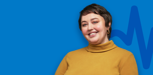 Smiling woman in mustard turtleneck on blue