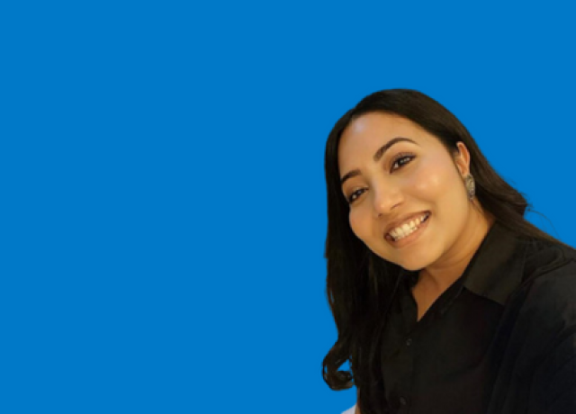 Person smiling in black top on blue background