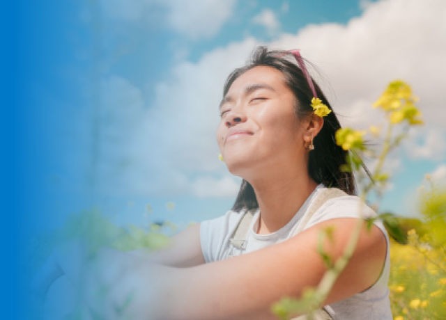 Person relaxing in a sunny field under blue sky.