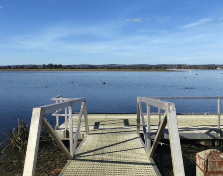 Lakeside jetty with calm water under clear blue sky