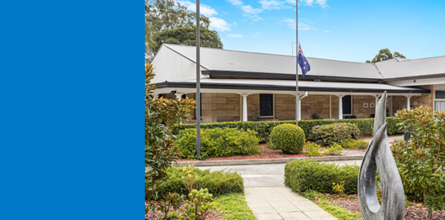 Landscaped path to low building with flagpoles