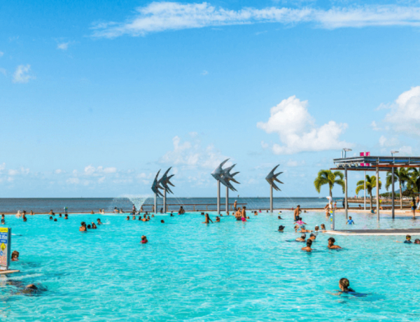 People in resort pool by ocean sculptures