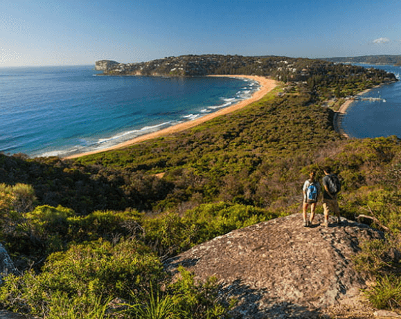 Two people overlooking a curved coastal bay