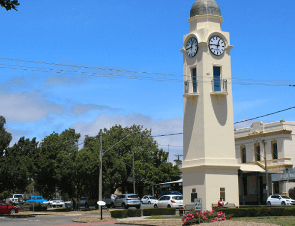 Street clock tower with cars and trees