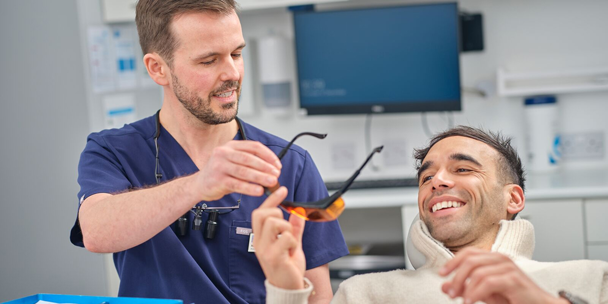 Dental professional handing protective glasses to patient