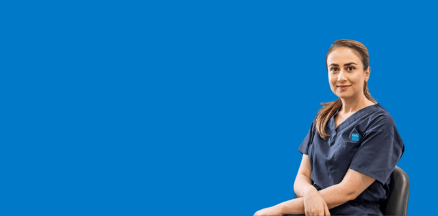 Woman in scrubs sitting against blue background