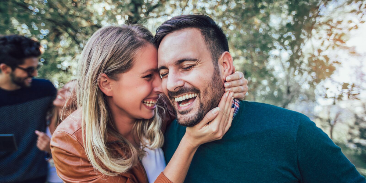 Two adults laughing closely outdoors