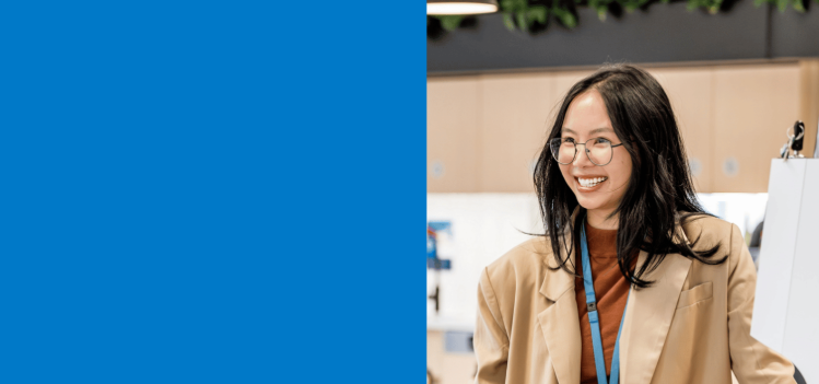 Person standing in an office workspace beside a blue panel