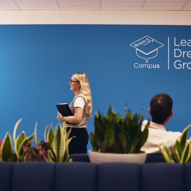 Person walking through campus lounge with tablet in hand.
