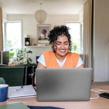 Person smiling using laptop at home desk