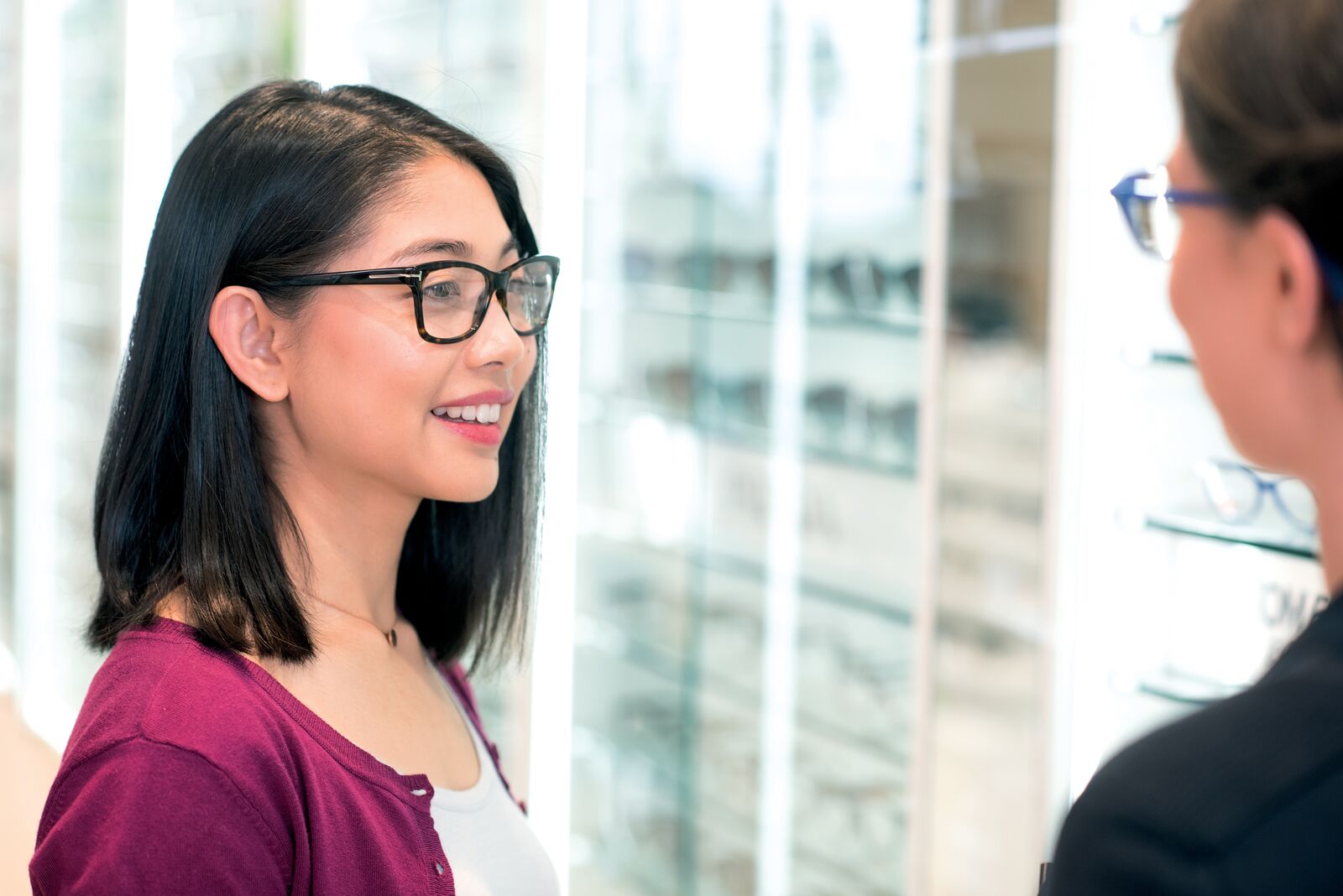 Woman trying on glasses with assistant