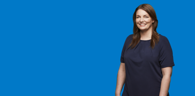Smiling woman in navy top on blue background