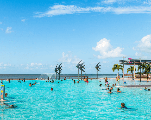 People swimming in seaside pool with sculptures