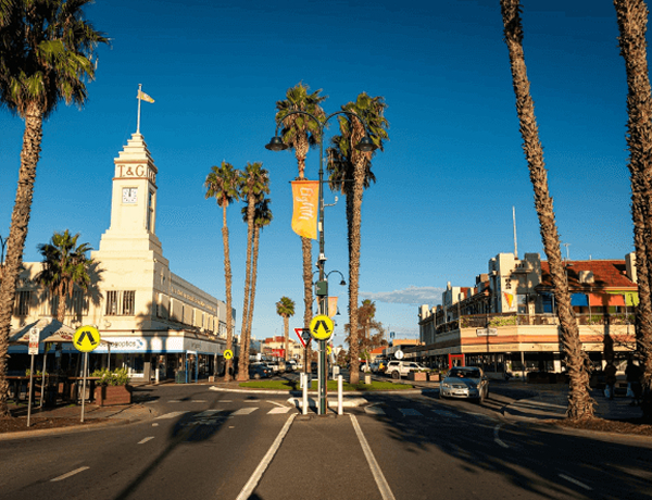 Palm-lined street with clock tower and shops