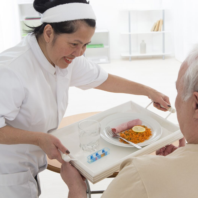 Care worker serving a meal to an elderly man