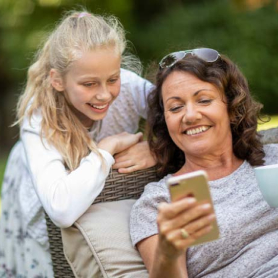Child and woman looking at smartphone outdoors