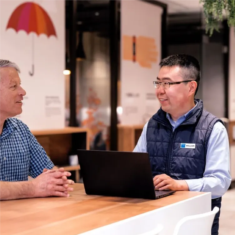 Two people discussing work at laptop