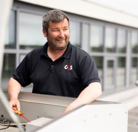 Smiling man in G4S shirt working on outdoor equipment