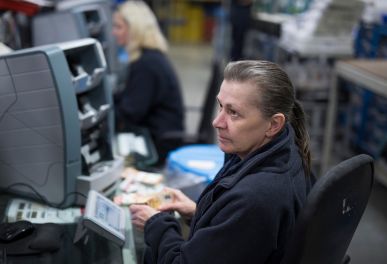 Woman counting banknotes at cash processing desk.