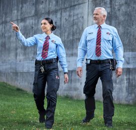 Two G4S officers patrol outdoors in uniform gear.