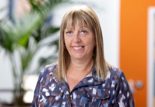 Smiling woman in patterned shirt in office setting.