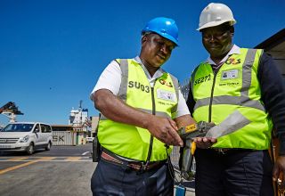 Two workers in safety gear inspecting equipment.