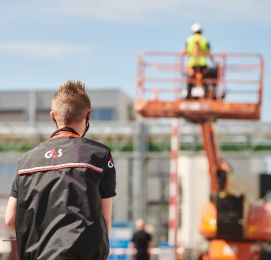 Construction worker on lift, another person in foreground.