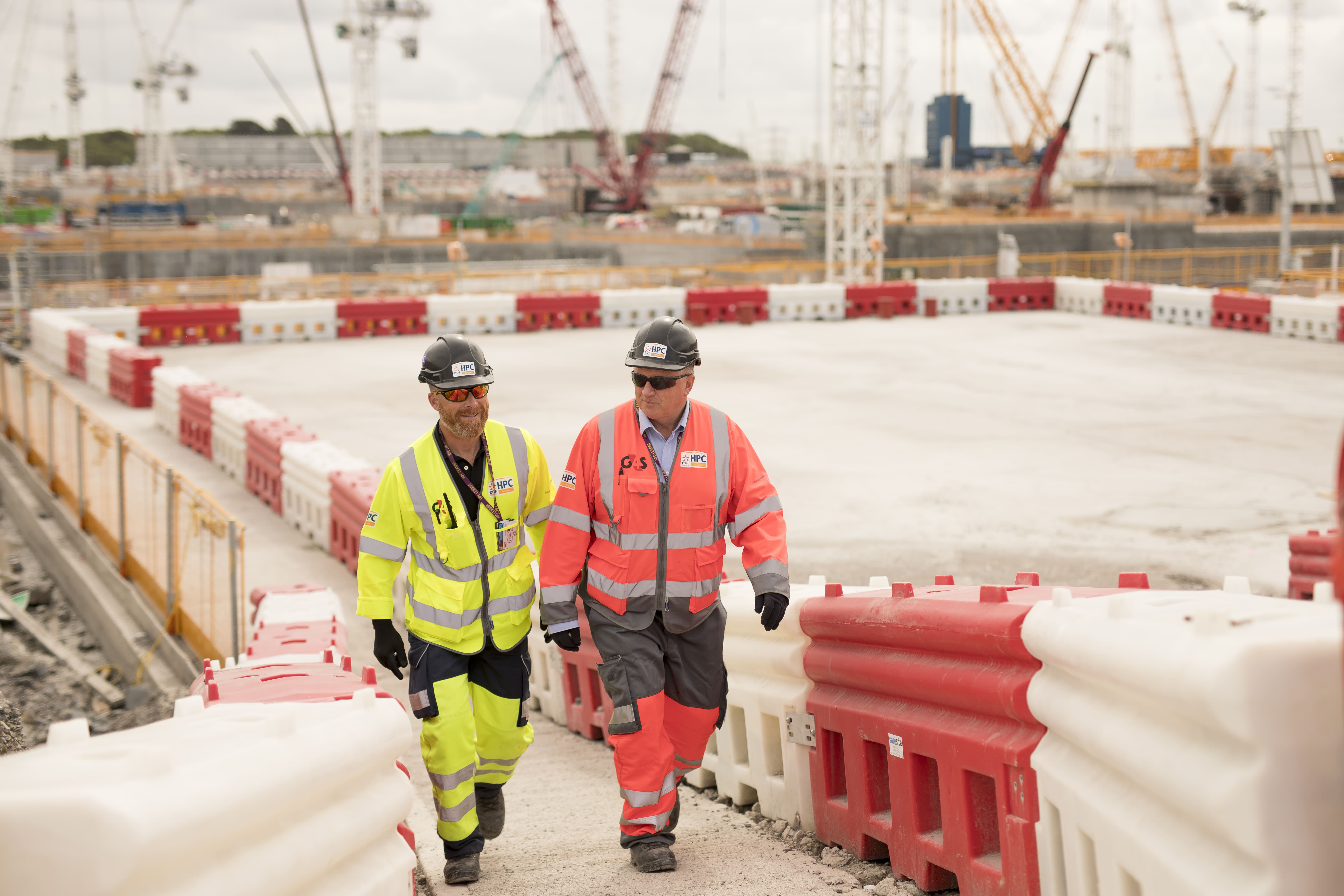 Two workers in hi-vis gear walking at construction