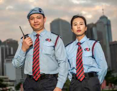 Two uniformed security guards in city background.