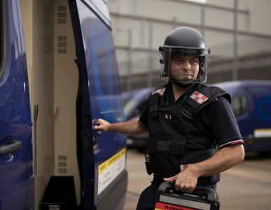 Security guard with helmet opening armoured van door.