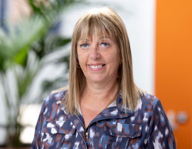Smiling woman in patterned shirt in office setting.
