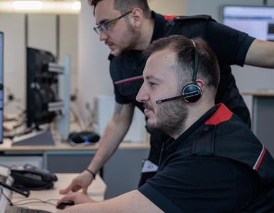 Two men working at desks with many computers screens.