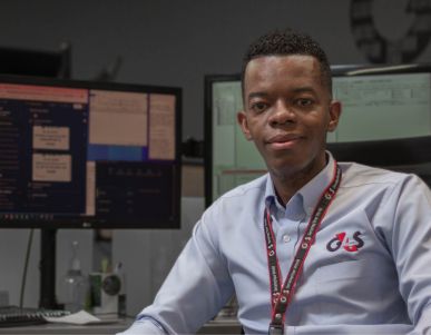 Man at desk with multiple monitors in control room.